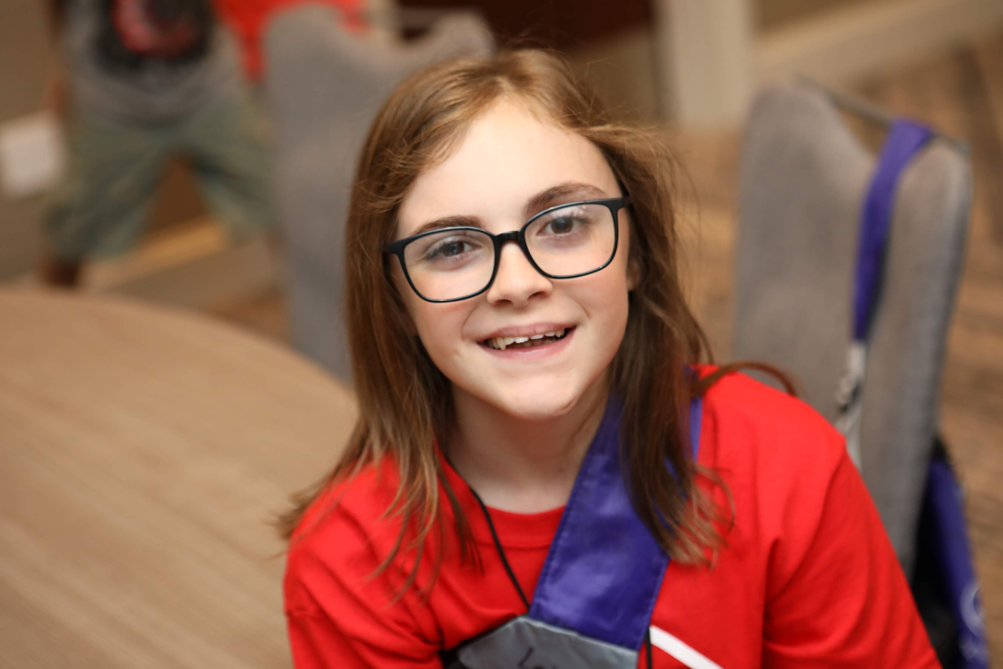 young girl with medium brown hair and glasses with VEDS smiling at the camera