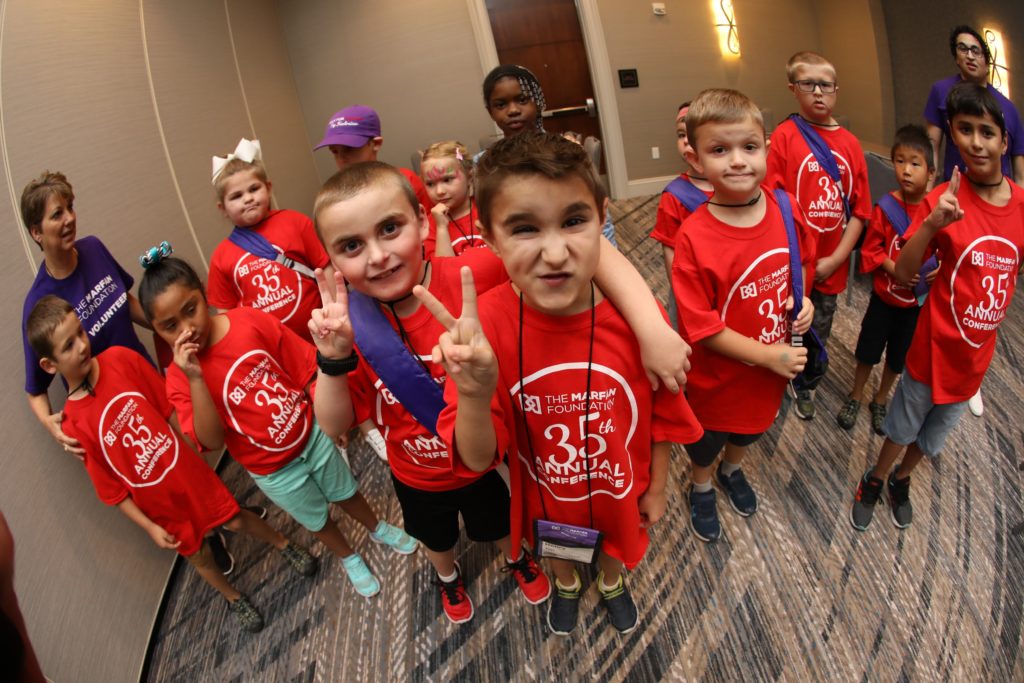 group of kids in red shirts smiling and making peace sign at camera