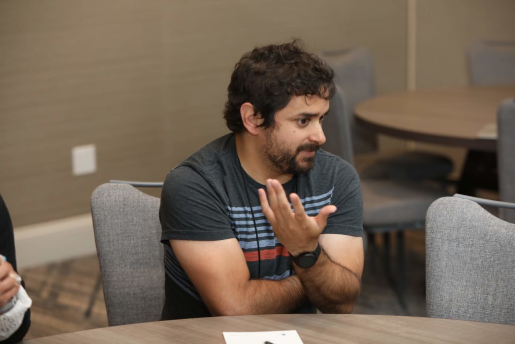 man with dark hair and gray shirt asking a question