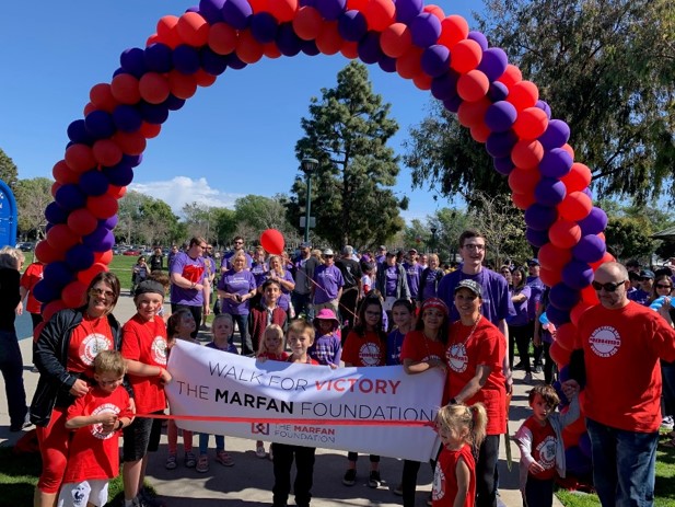 Team VEDS at S California Walk for Victory. People in red and purple shirts and balloons with a sign that says "walk for victory- The Marfan Foundatoin"