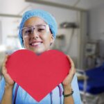 female nurse holding a paper heart and smiling