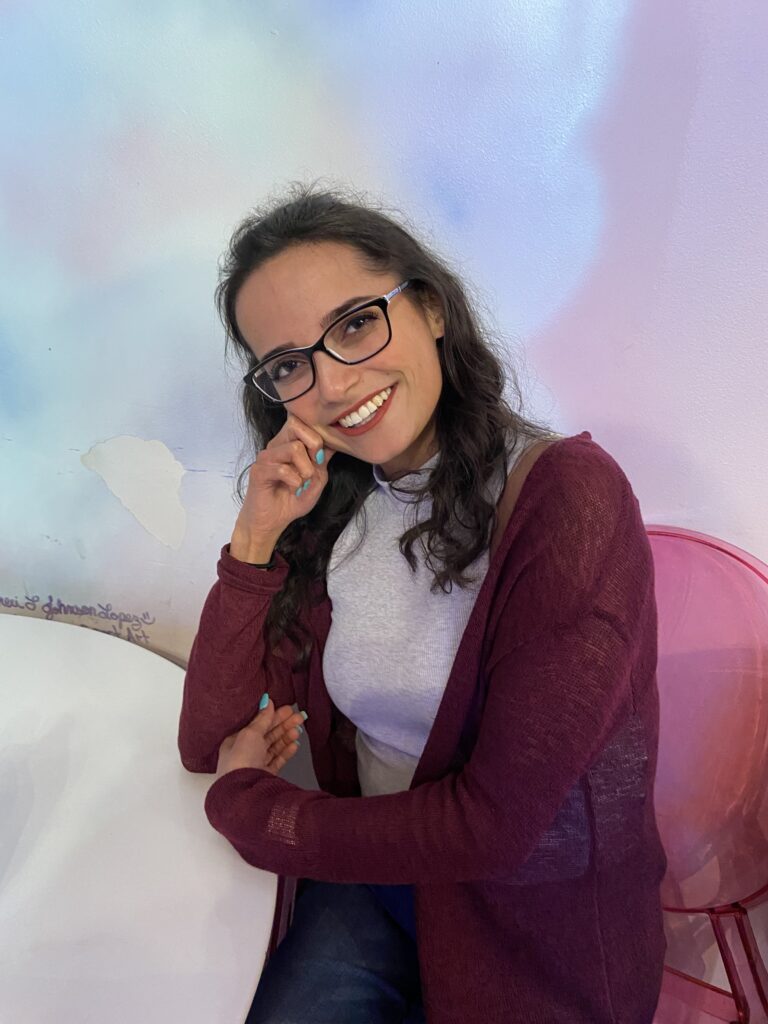 Young woman with dark brown curly hair and glasses