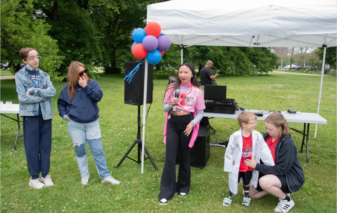 Maia speaks into a microphone at the Chicago Walk for Victory, raising awareness for Vascular Ehlers-Danlos syndrome.